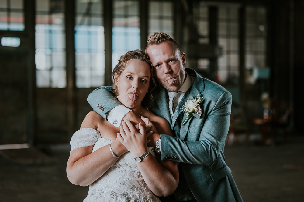 Bruidspaar steekt de tongen uit. Bruidsreportage in de Sluisfabriek in Drachten door trouwfotograaf Nickie Fotografie uit Friesland.