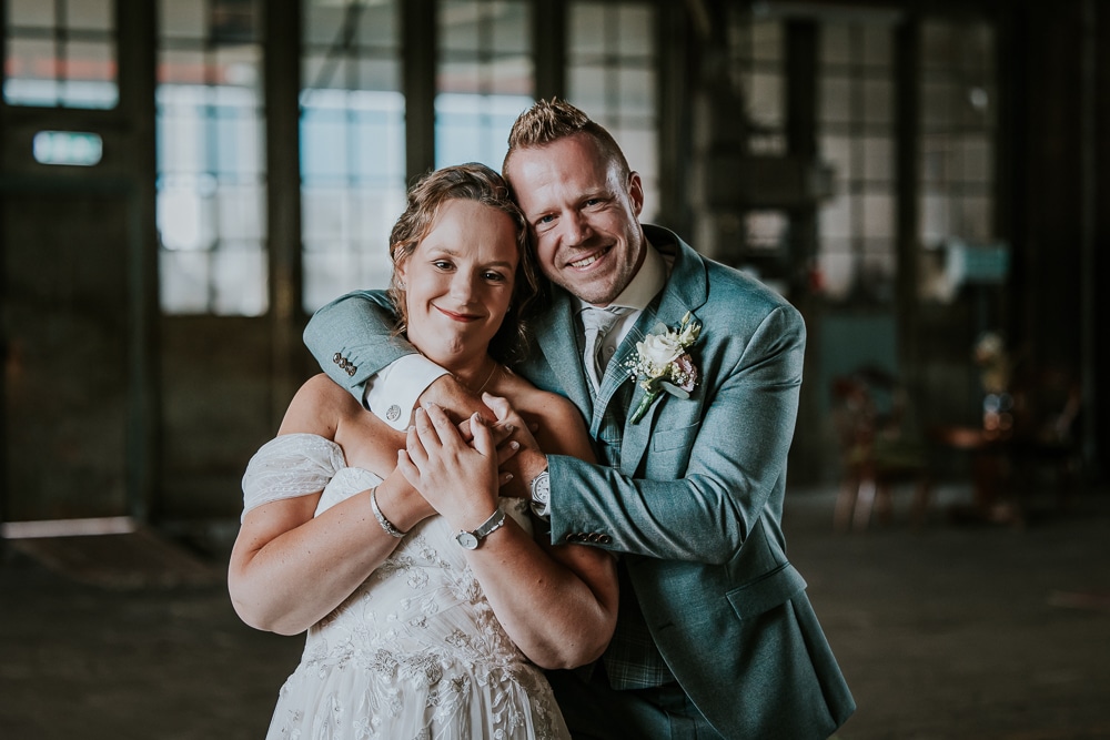 Trouwreportage in de Sluisfabriek in Drachten door bruidsfotograaf NIckie Fotografie. Gezellig portret van het bruidspaar.