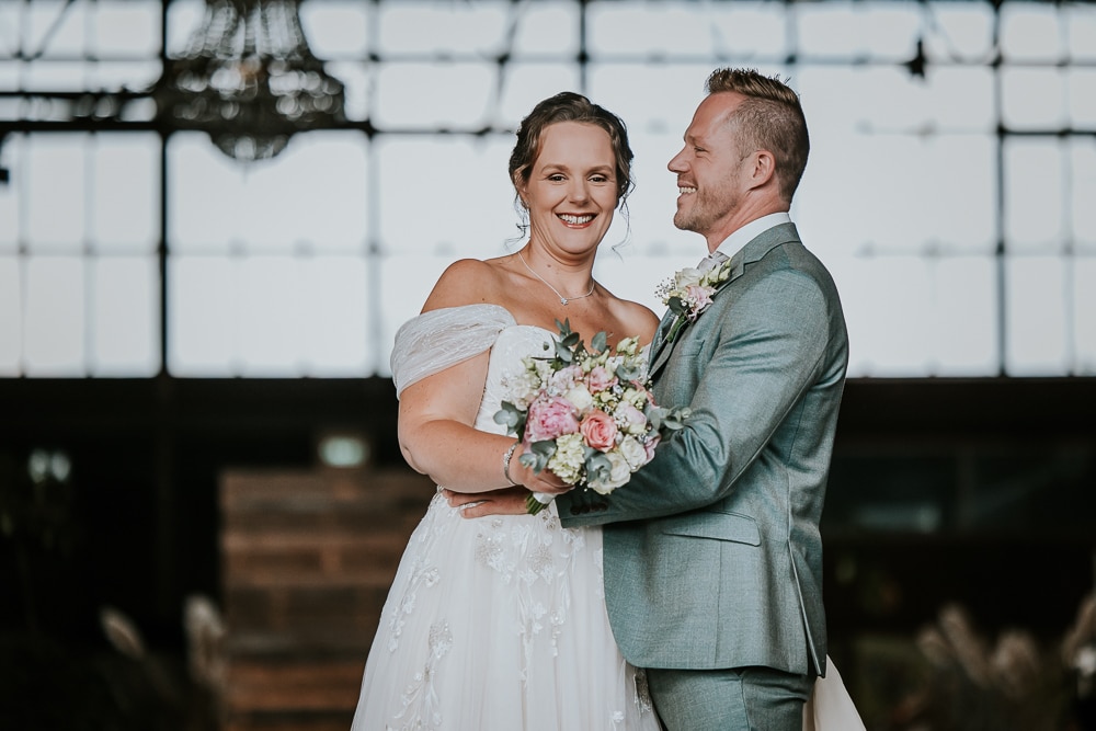 Trouwen in Drachten. Bruidsfotografie in de Sluisfabriek door fotograaf Nickie Fotografie uit Friesland. De bruidegom kijkt zijn bruid heel liefdevol aan.