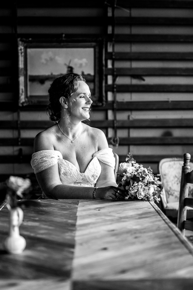 Portret van een zittende bruid aan vissegraat tafel in de Sluisfabriek door huwlelijksfotograaf Nickie Fotografie uit Friesland.