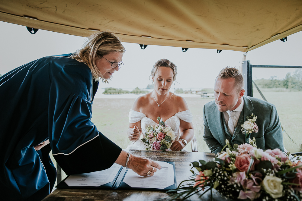 Bruidspaar zet de handtekening op de huwelijksakte. Trouwfotografie door bruidsfotograaf Nickie Fotografie uit Friesland. Trouwen bij de Lyen.