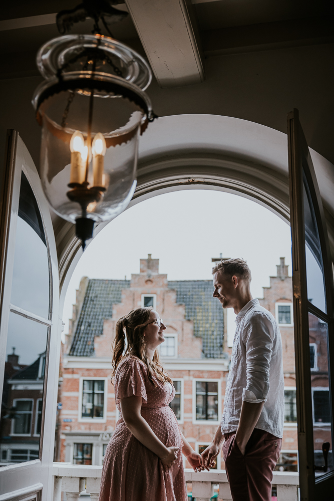 Fotograaf Friesland. Trouwen in Dokkum. De balkonscene. Het bruidspaar kijkt elkaar liefdevol aan. Trouwfotografie door bruidsfotograaf Nickie Fotografie.