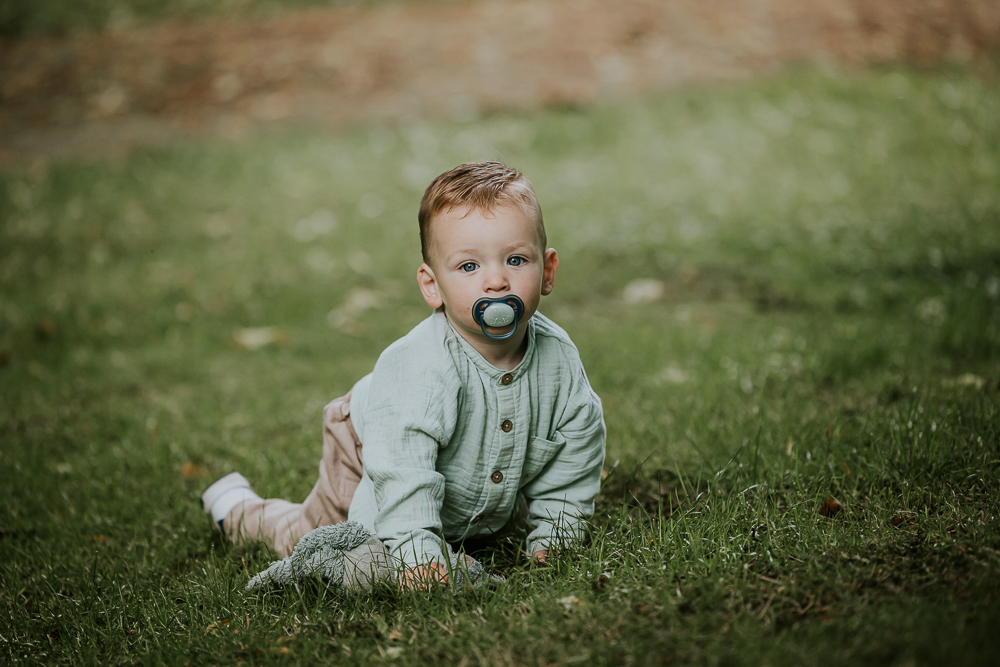 Kinderfotograaf Friesland Nickie Fotografie. Portret van kruipende dreumes in het gras met speen in de mond.