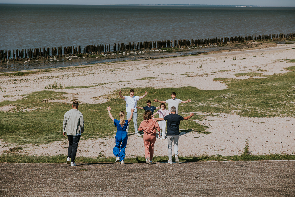 Spontane fotoshoot bij de Waddenzee door fotograaf Nickie Fotografie. De ouders rennen de dijk af naar hun kids.