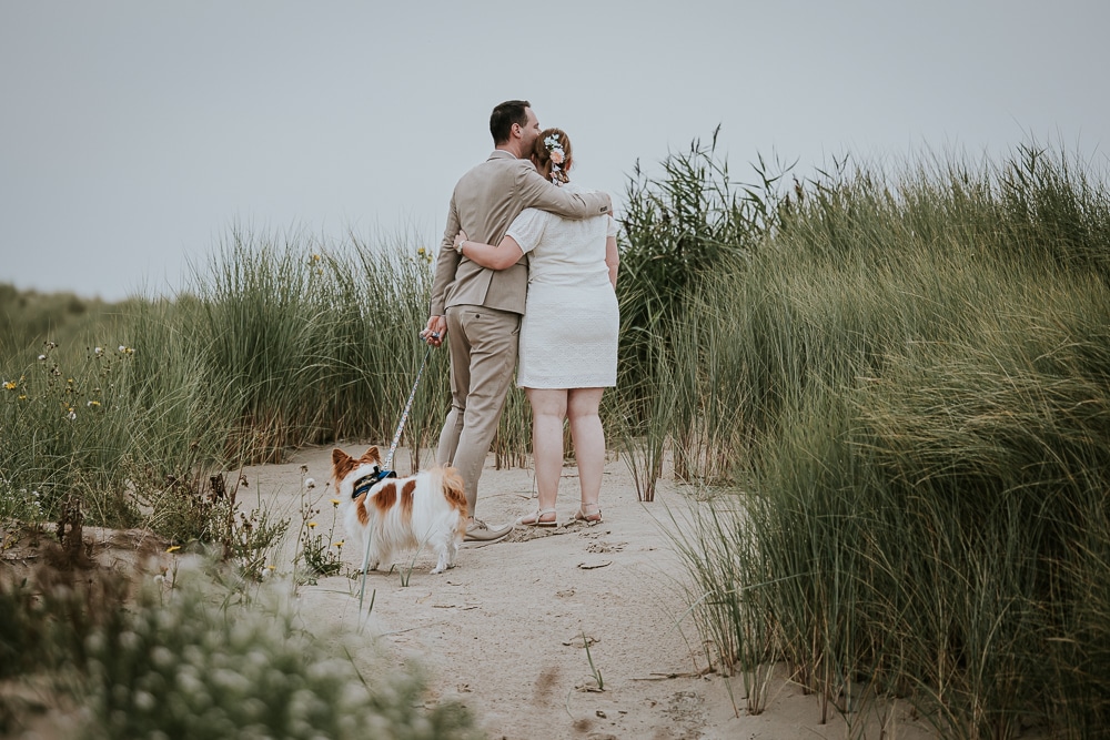 Trouwfotograaf Ameland, Nickie Fotografie. Het bruidspaar in de duinen met hun hond.