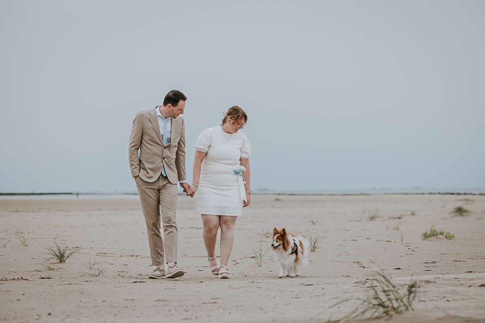 Bruiloft op het strand. Bruid en bruidegom laten hun hond uit op Ameland. Bruidsreportage door bruidsfotograaf Nickie Fotografie uit Friesland.