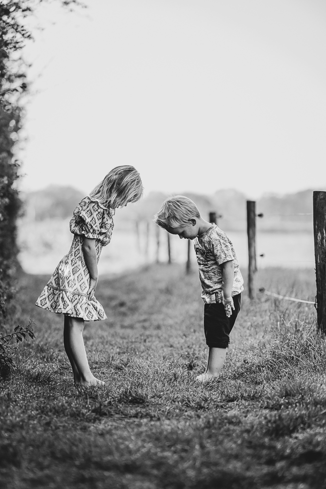 Zwart-wit kinderfotografie Friesland door fotograaf Nickie Fotografie. De kinderen kijken of hun voeten al vies zijn.