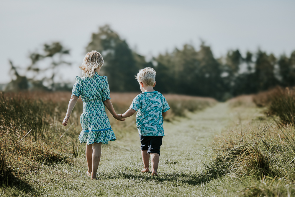 Fotograaf Gronignen. KInderportret door Nickie Fotografie. De kinderen lopen hand in hand over het graspaadje.