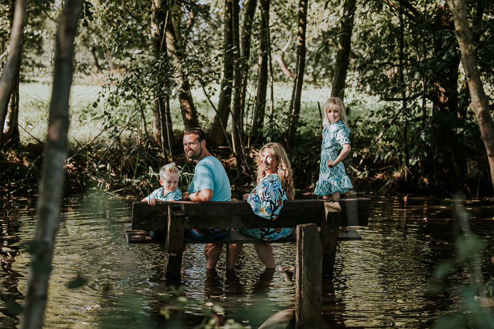 Zittend op het bankje in het water tijdens de korte wandeling van het blotevoetenpad in Opende. Gezinsreportage door fotograaf Nickie. Fotografie