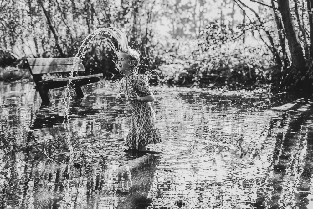 Zwart-wit actieportret van een meisje in het water door Nickie Fotografie.