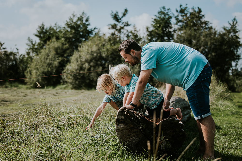 Gezinsreportage Groningen. De kinderen en vader kijken naar een sprinkhaan. Lifestyle fotoshoot door Nickie Fotografie.