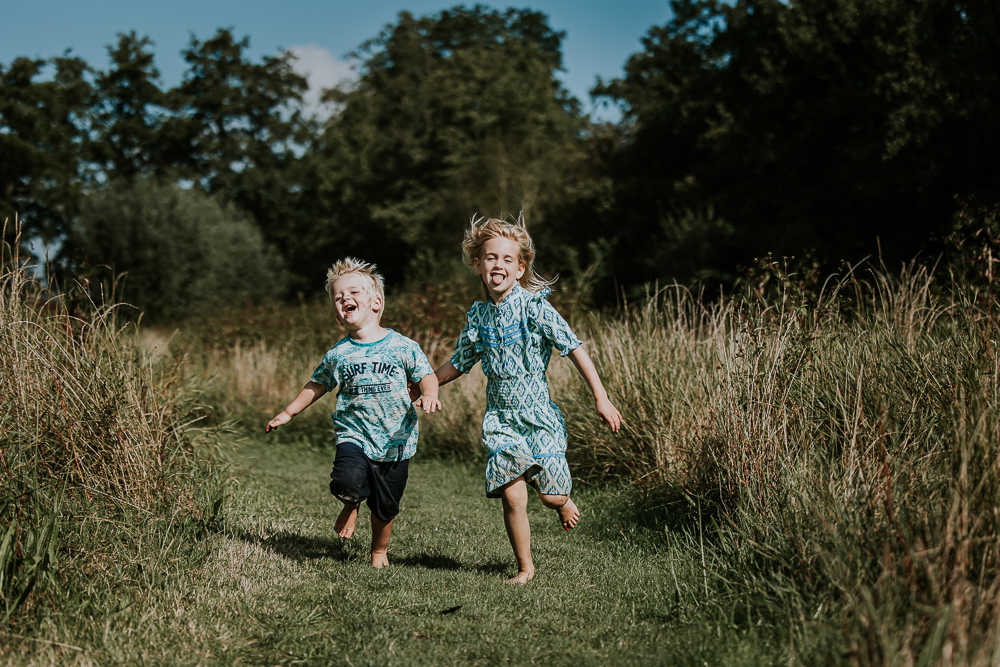 Fotoshoot Groningen. Twee kinderen rennen over het graspaadje. Fotografie door fotograaf NIckie Fotografie.