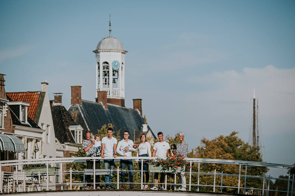 Fotoshoot Dokkum. door fotograaf Nickie Fotografie. Portret van de famlie op het witte bruggetje met het stadhuis op de achtergrond. 