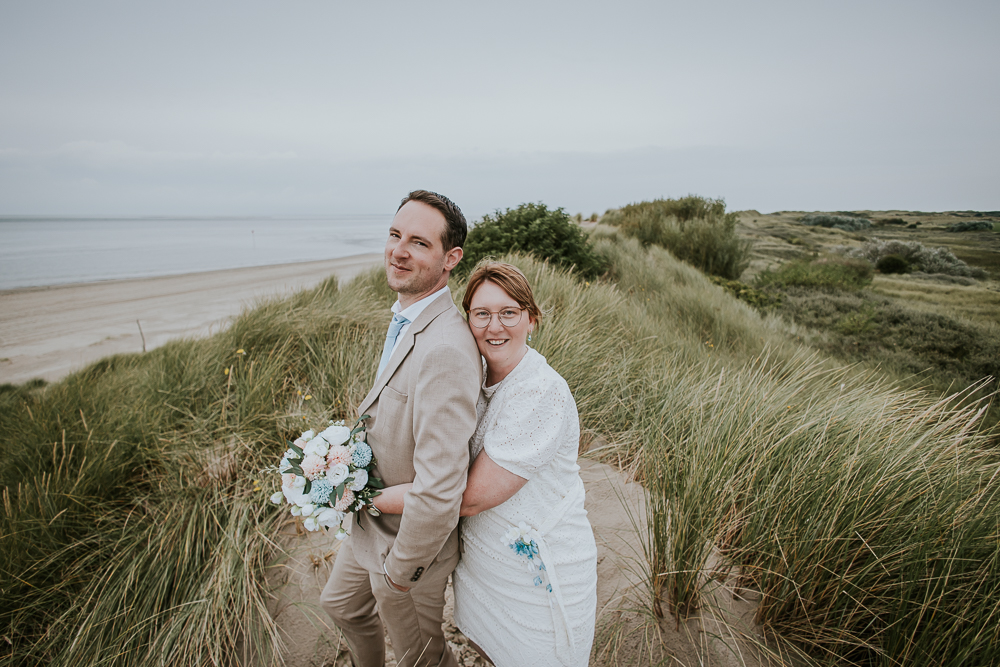 Trouwfotograaf Ameland. Het bruidspaar staat bovenop de duin. Huwelijksfotografie door bruidsfotograaf Nickie Fotografie uit Friesland.