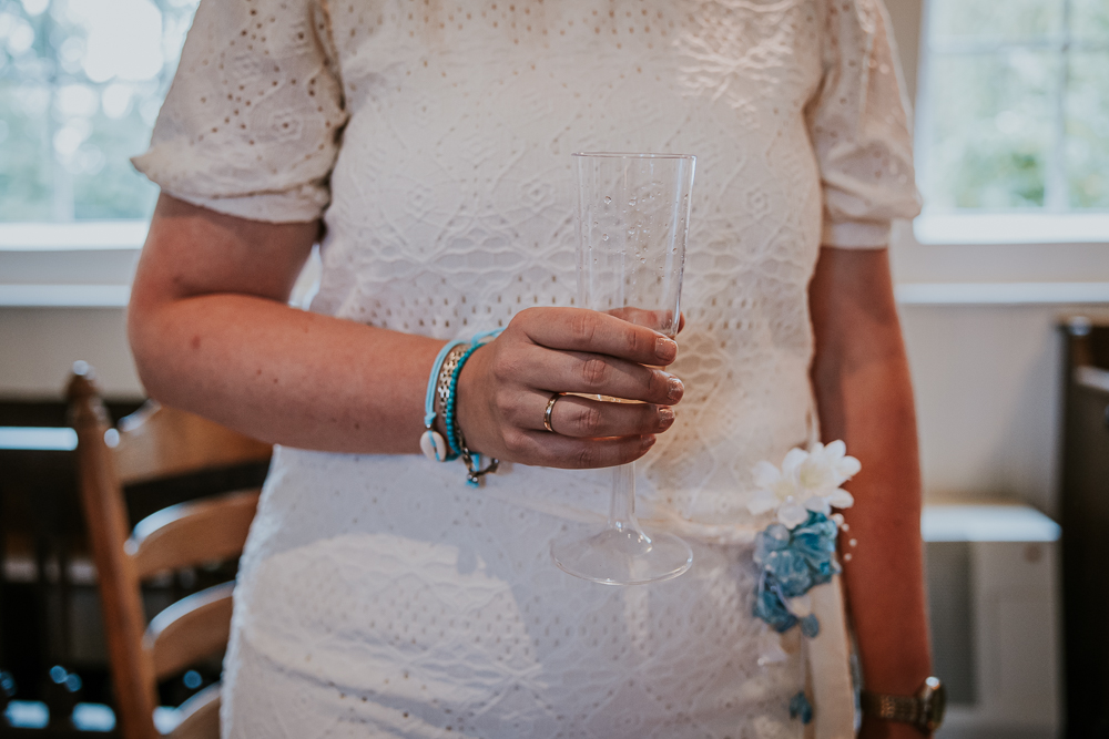 Bruid staat klaar om te toosten met haar glas champagne. Trouwreportage door bruidsfotograaf Nickie fotografie uit Friesland.