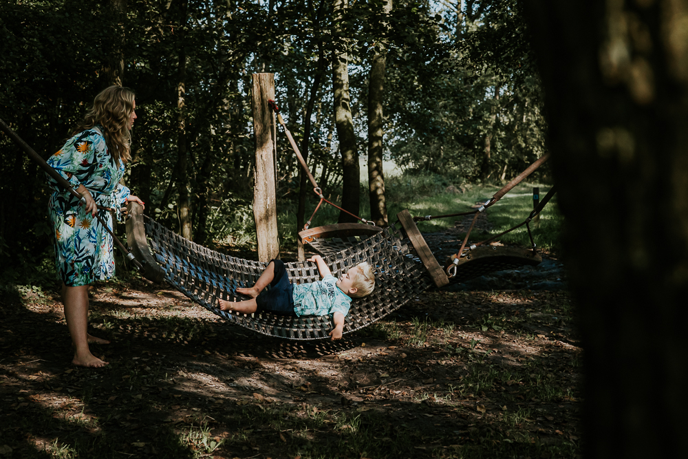 Schommelen in een van de hangmatten tijdens de wandelroute van het blotevoetenpad. Fotosessie door fotograaf NIckie Fotografie.