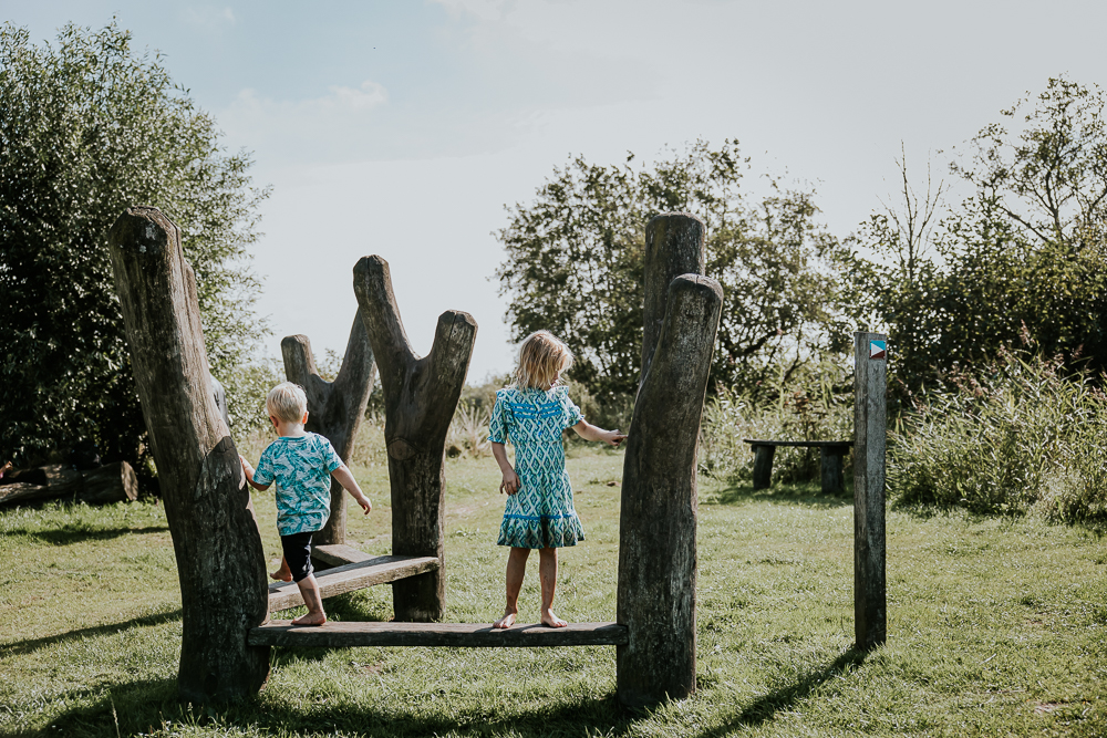 De kinderen spelen op een van de speeltoestellen van het blotevoetenpad. Kinderfotografie door fotograaf NIckie Fotografie.