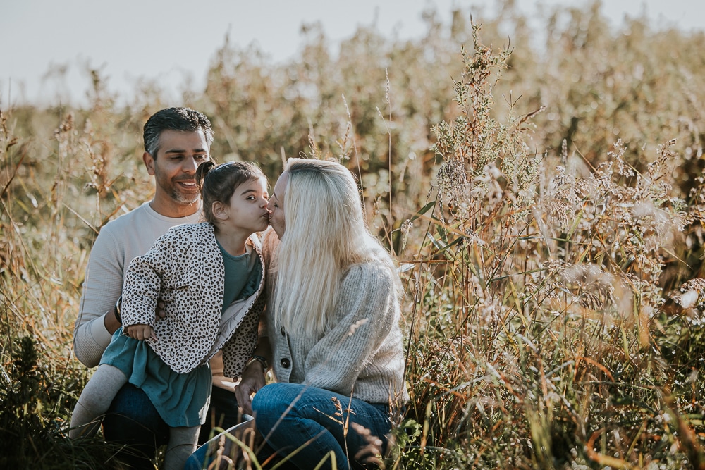 Fotograaf Lauwersoog. Gezellig gezinsportret in het hoge gras bij de surfspot door Nickie Fotografie.