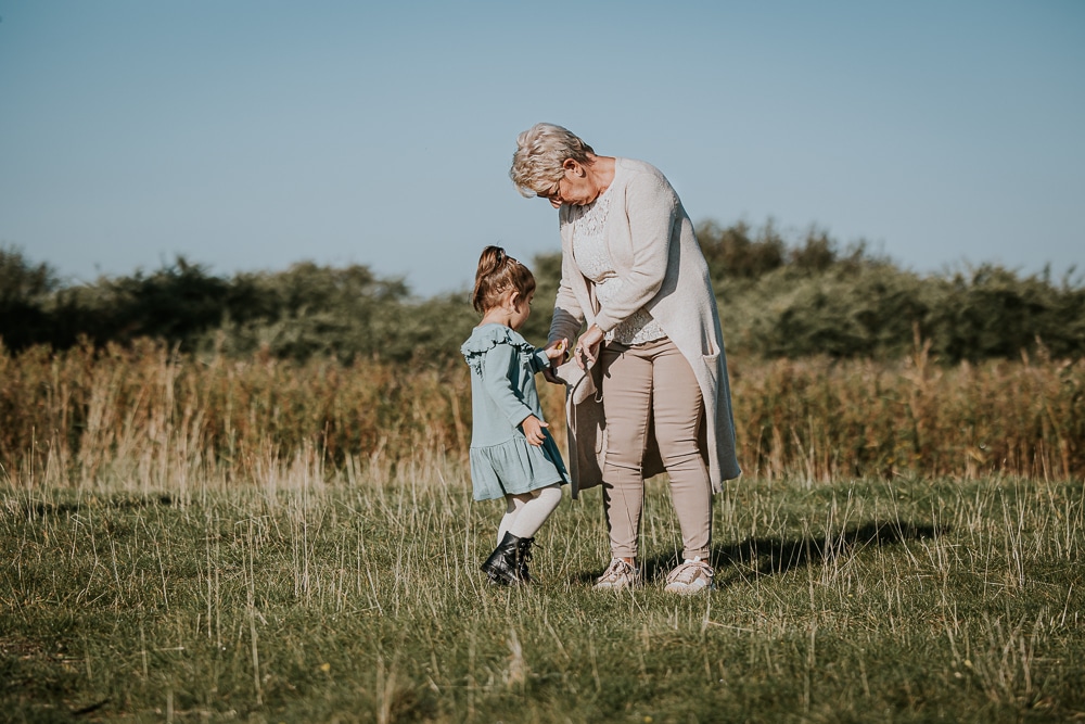  Ons gezin - fotoreportage in het Lauwersmeergebied. Kleindochter doet haar gevonden schelpjes in de vestzak van oma. Lifestyle familieshoot door fotograaf Nickie Fotografie uit Friesland.