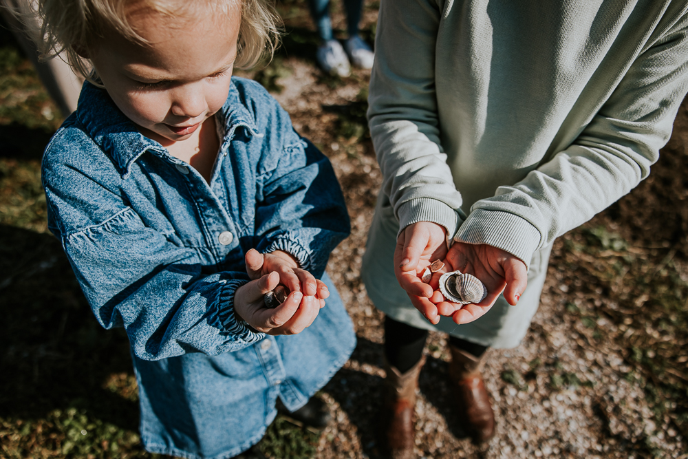 De kinderen laten hun gevonden schelpjes zien. Lifestyle familieshoot in het Lauwersmeergebied door fotograaf Nickie Fotografie.