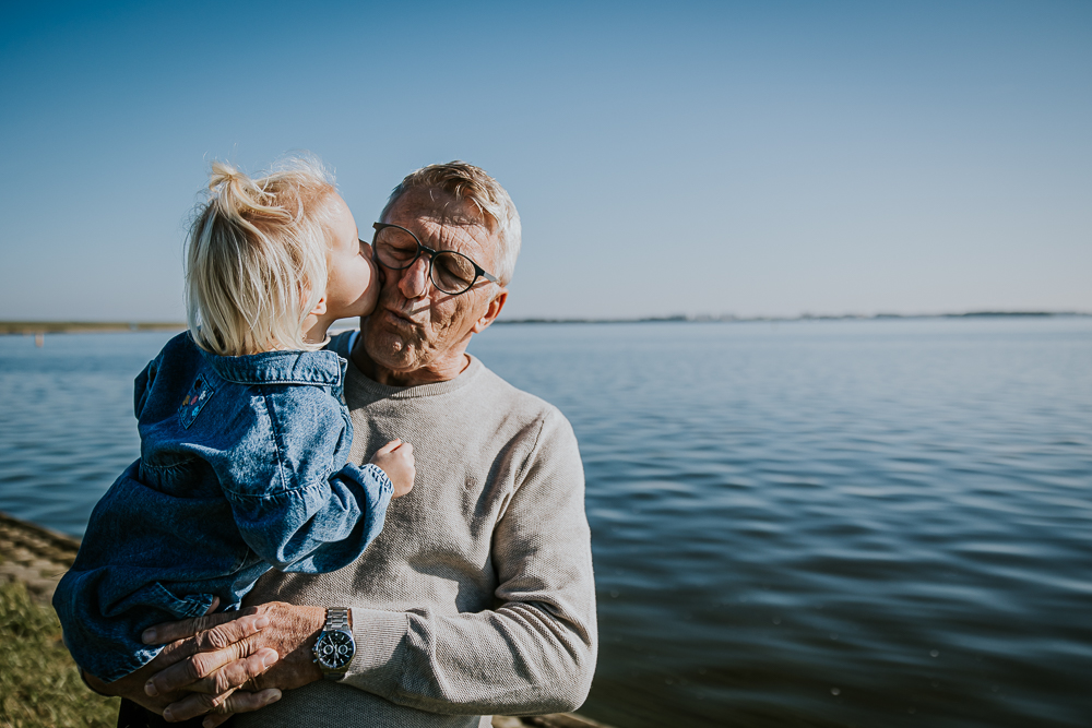 Kleindochter geeft opa een dikke zoen. Familiefotoreportage door fotograaf NIckie Fotografie uit Dokkum, Friesland.