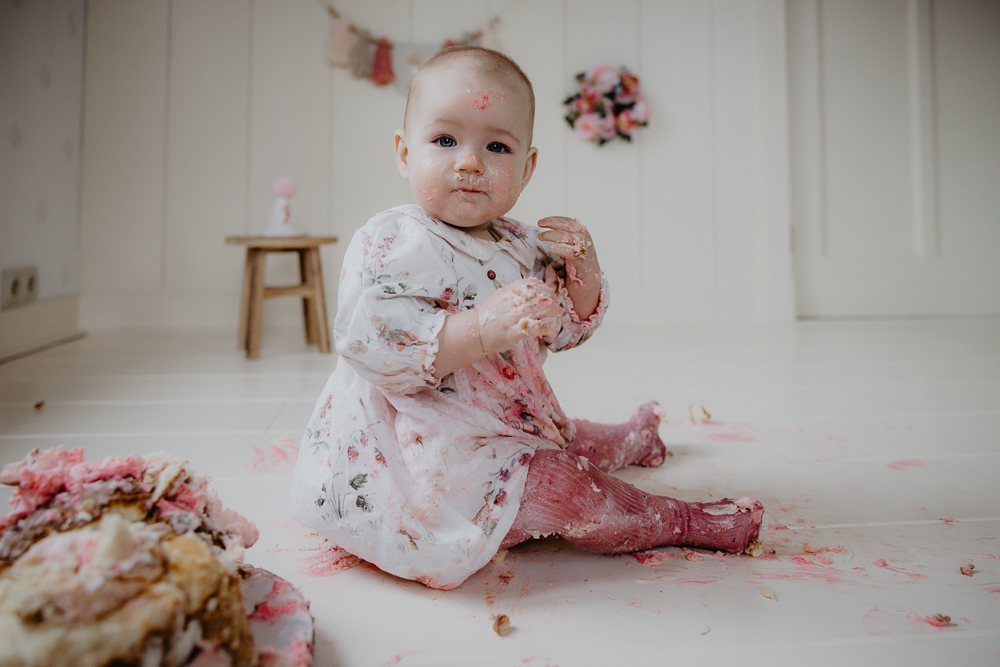 Fotoshoot 1 jaar door fotograaf Nickie Fotografie uit Dokkum. Meisje is lekker aan het genieten van de verjaardagstaart. 