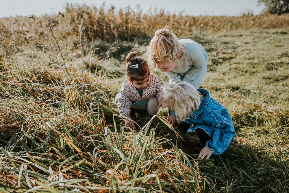 Fotoshoot Lauwersoog. Drie meisjes zoeken beestjes in het hoge gras. Lifestyle familieshoot door fotograaf Nickie Fotografie.