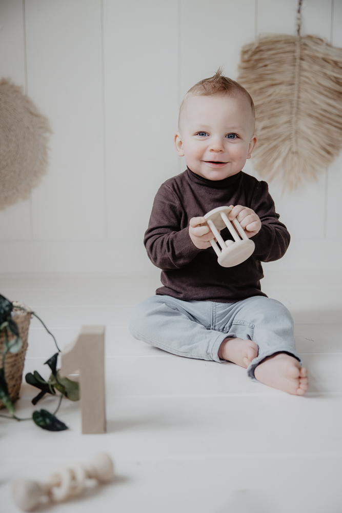 Portret in bohemianstijl vooraf de cakesmash door fotograaf Nickie Fotografie. Jongetje zit met hout rammelaar te spelen.