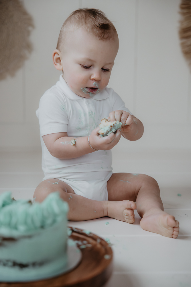 Eerste verjaardag vieren. Baby jongetje vindt de groene taart erg interessant. Fotosessie door fotograaf Nickie Fotografie uit Dokkum, Friesland.