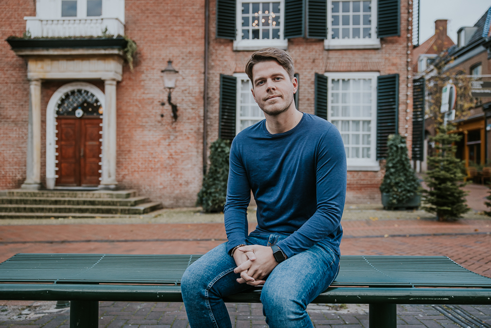 Profielportret, zittend op het bankje voor het oude Stadhuis van Dokkum. Fotoshoot door fotograaf Nickie Fotografie uit Friesland.