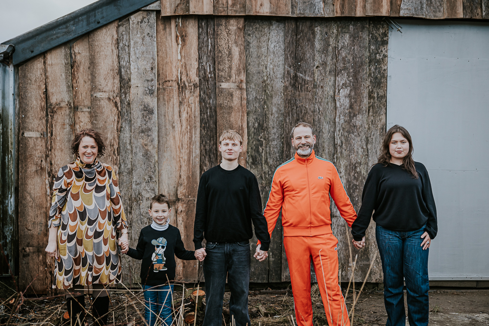 Industrieel gezinsshoot in Dokkum. Het hele gezin houdt elkaars handen vast. Fotosessie door fotograaf Nickie Fotografie uit 
 Friesland.