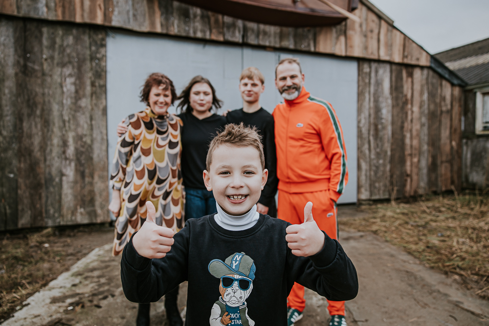 Industrieel gezinsshoot in Dokkum, Friesland door fotograaf Nickie Fotografie bij de oude Prins fabriek. Jongetje staat vooraan met twee duimen omhoog.