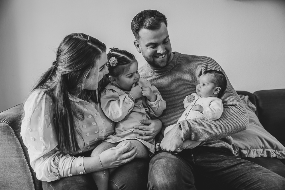 Fotograaf Friesland. Zwart-wit gezellig gezinsportret op de bank tijdens de babyshoot in Leeuwarden door Nickie Fotografie.