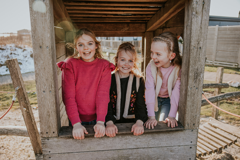 Fotograaf Lauwersoog. Vrolijk portret, van de drie zussen in het speelhuisje bij het Booze Wijf, door fotograaf NIckie Fotografie.