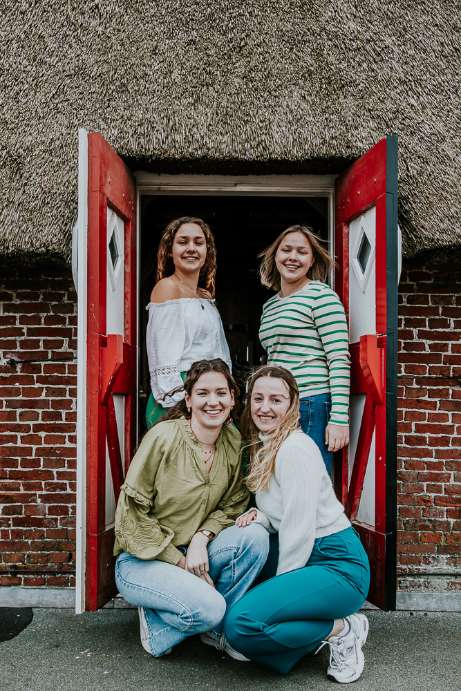 Portret van de vier vriendinnen bij de rode deurtjes naar het balkon van de molen. Fotosessie door fotograaf Nickie Fotografie uit Dokkum, Friesland.