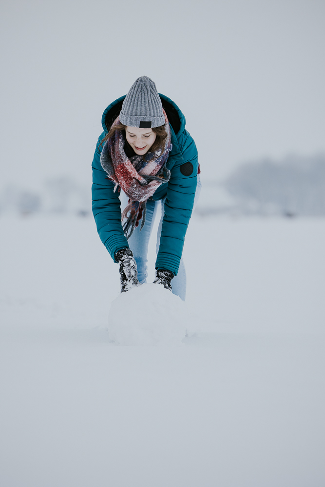 Fotoshoot in de sneeuw. Meisje rolt een sneeuwbal. Fotoreportage door fotograaf Nickie Fotografie uit Dokkum, Friesland.