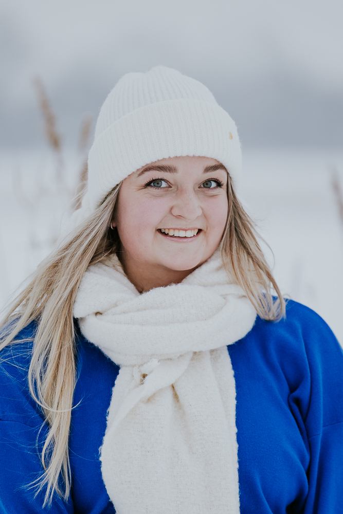 Winterfotografie. Portret van jonge dame in fel blauwe trui met warme muts en sjaal. Fotoshoot door fotograaf Nickie Fotografie uit Dokkum, Friesland.