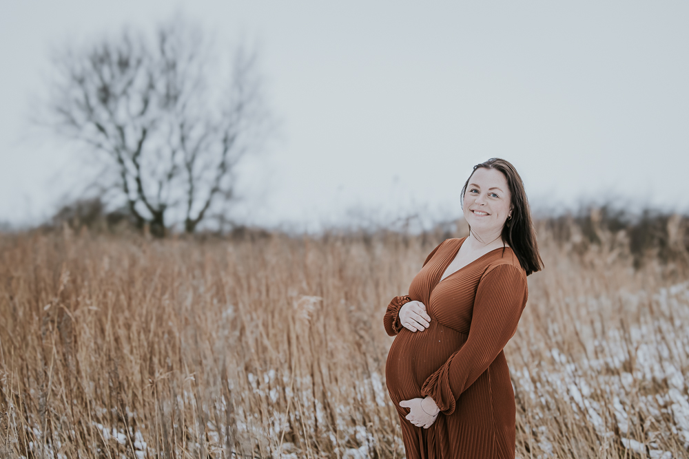 Zwangerschapshoot in de sneeuw met op de achtergrond een rietkraag. Fotosessie door fotograaf Nickie Fotografie uit Dokkum, Friesland.