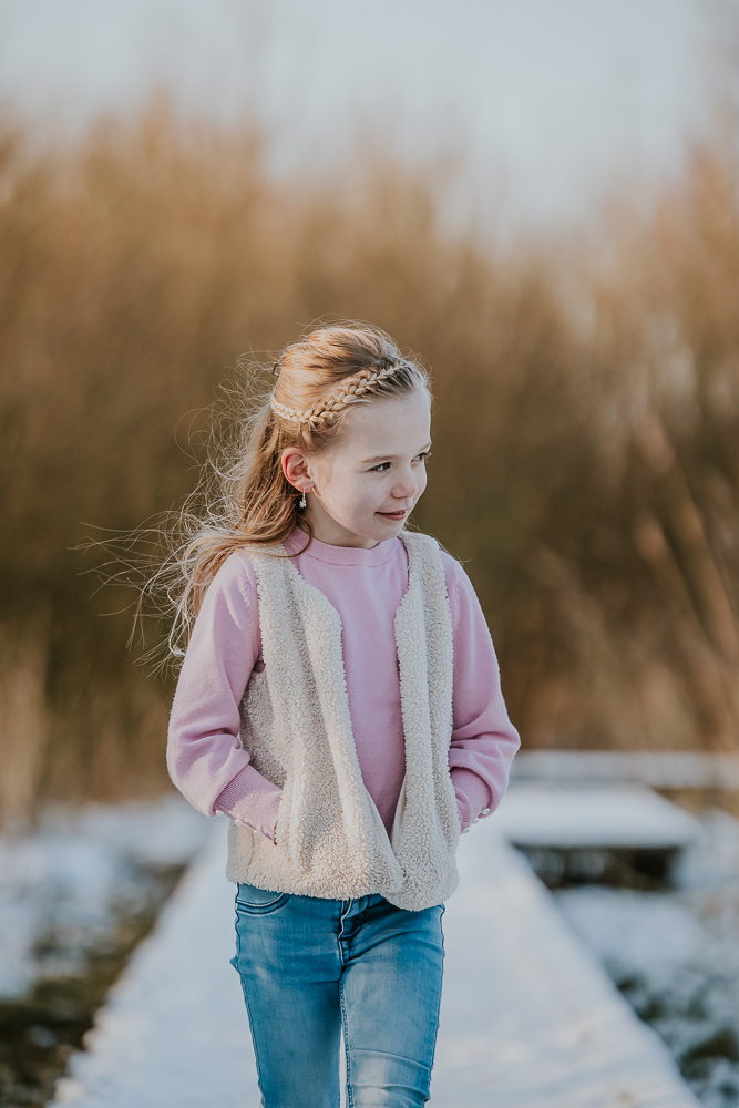 Fotoshoot in de sneeuw. Meisje wandelt over de houten vlonder. Kinderportret door fotograaf Nickie Fotografie uit Dokkum, Friesland.