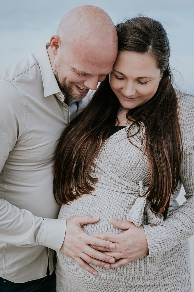 Vader en moeder voelen aan de bolle buik. Zwangerschapsshoot door fotograaf Nickie Fotografie uit Friesland.