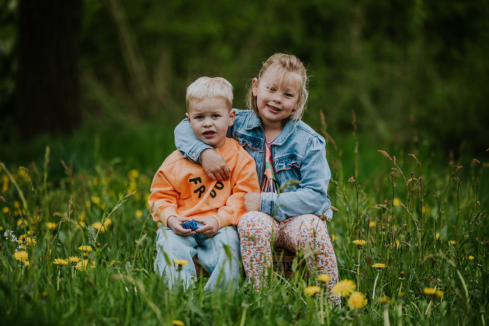Fotoshoot Dokkum. Portret van broer en zus tussen de paardenbloemen door fotograaf Nickie Fotografie uit Friesland.
