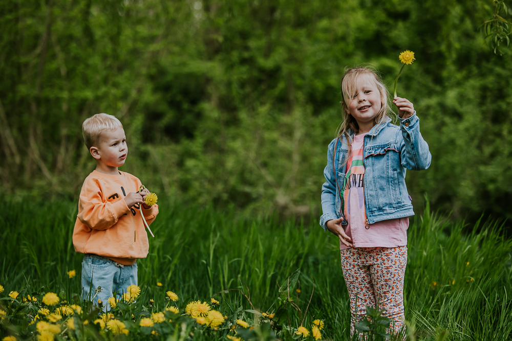 Kindershoot Dokkum door fotograaf Nickie Fotografie. Fotoreportage van zus en broertje in het grasveld terwijl ze bloemen aan het plukken zijn.