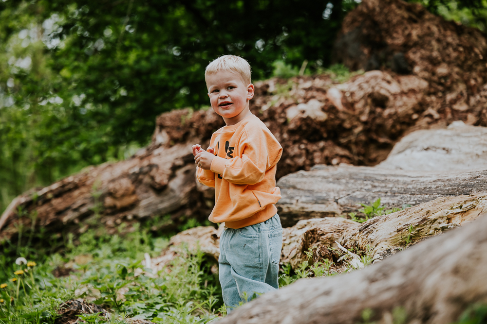Fotograaf Dokkum. Portret van jongetje tussen de grote boomstammen door Nickie Fotografie.