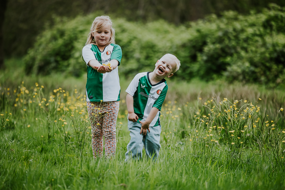 Kinderfotografie tussen de boterbloemen in een groen-wit Feyenoord shirtje door fotograaf Nickie Fotografie uit Dokkum, Friesland.