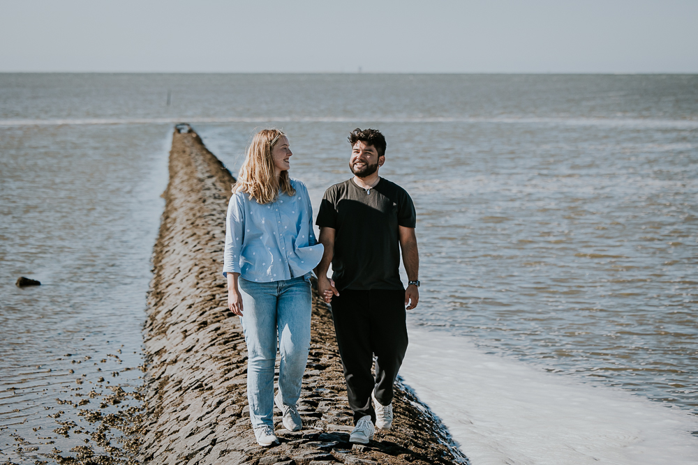 Fotoshoot Friesland. Stelletje loopt hand in hand over het dammetje in de Waddenzee. Portret door fotograaf Nickie Fotografie.