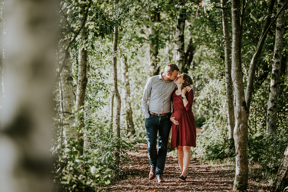Fotoshoot in De Deelen. De aanstaande ouders geven elkaar een kusje tijdens de wandeling. Zwangerschapsfotografie door zwangerschapsfotograaf Nickie Fotografie uit Friesland.
