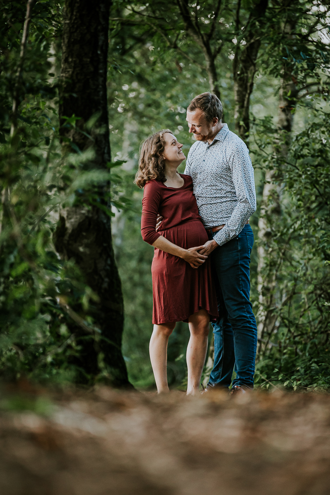 Loveshoot met bolle buik. De aanstaande ouders kijken elkaar liefdevol in de ogen aan terwijl ze elkaar omarmen. Zwangerschapsshoot door fotograaf Nickie Fotografie uit Friesland.