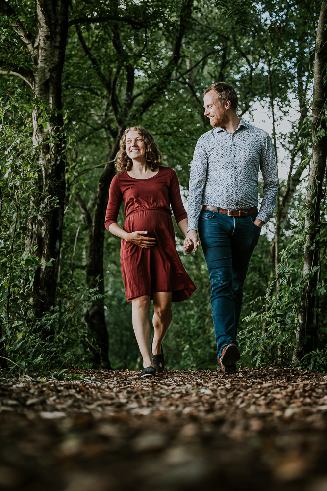 Bollebuikshoot in een natuurgebied door fotograaf Nickie Fotografie uit Friesland. De aanstaande ouders wandelen hand in hand terwijl de vader zijn partner liefdevol aankijkt.