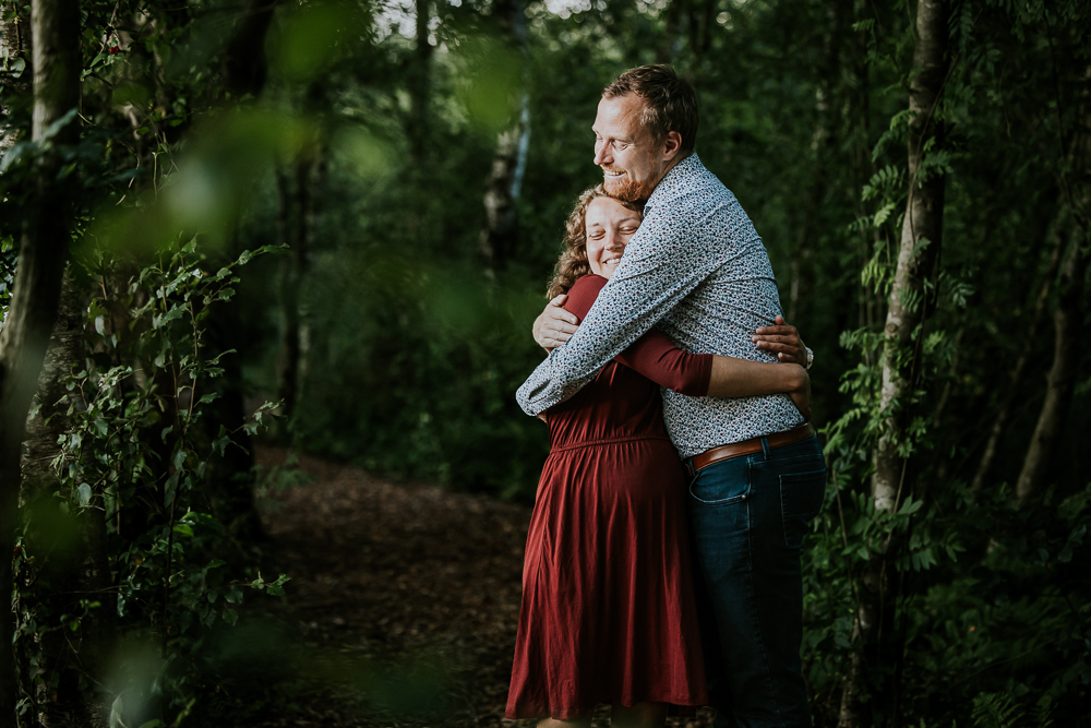 Liefdevolle knuffel tijdens de loveshoot in een natuurgebied in Friesland. Fotoshoot door zwangerschapsfotograaf Nickie Fotografie.