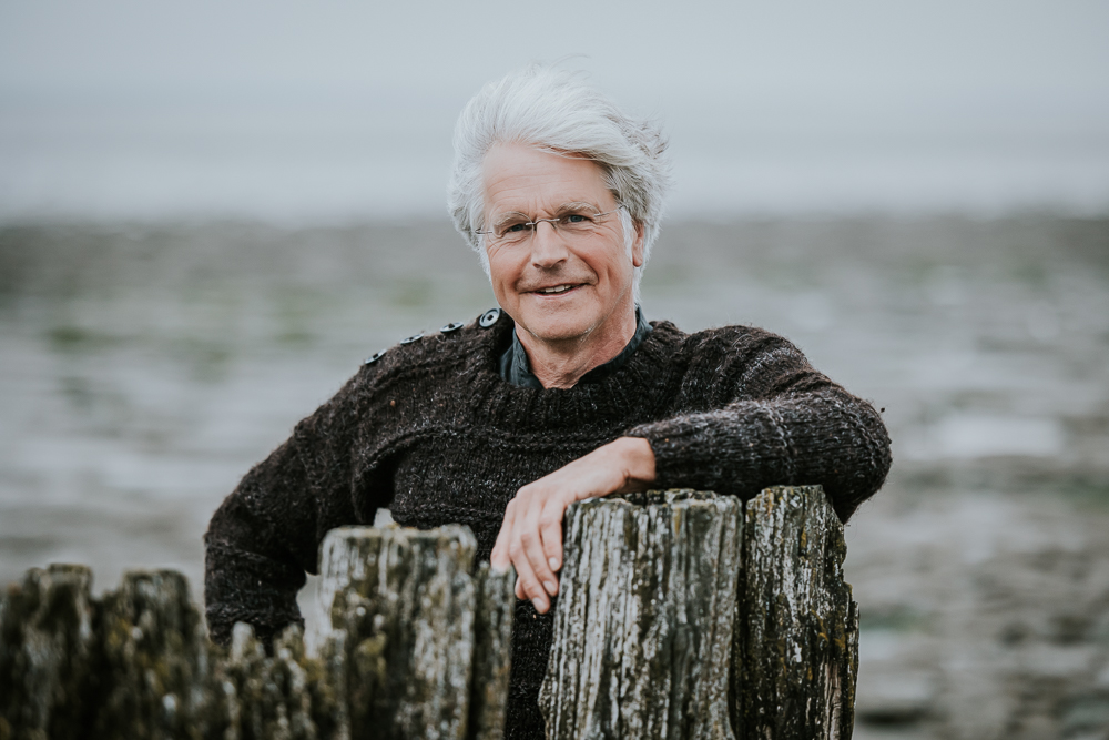 Fotograaf Friesland. Portret van man in bruine wollen visserstrui bij de Waddenzee. Bedrijfsfotografie door Nickie Fotografie.